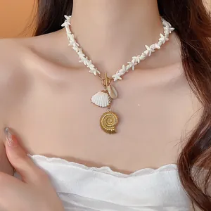 Close-up of a beach style necklace with white shell beads and gold nautical pendants.