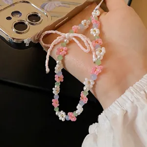 Sweet floral beaded phone charm featuring pearls and a delicate pink bow held by a hand