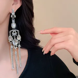 Close-up detail of silver-tone tassel earrings with waterdrop rhinestones worn by a model