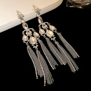 Close-up of silver-plated chandelier earrings with teardrop crystals and chain tassels.