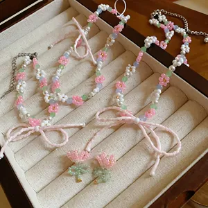 Detailed view of beaded flower and bow necklace with matching earrings in box