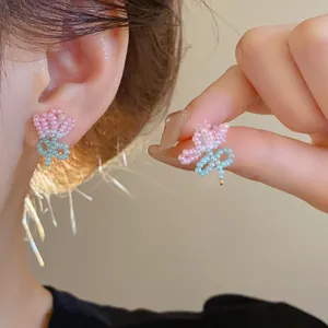 Close-up view of sweet handmade pink and blue beaded butterfly earrings worn on a model ear.