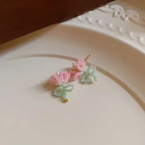 Macro view of sweet pastoral style pink and green handmade beaded bow earrings.