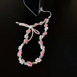 Close-up of sweet beaded flower lanyard with pink bow detail on black background.