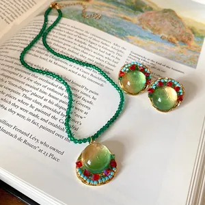 Detail of vintage French green beaded necklace and earrings set on an open book