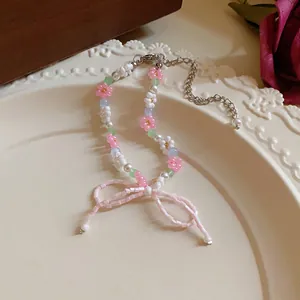 Detailed macro view of pastoral style beaded necklace featuring pink flowers and a bow pendant
