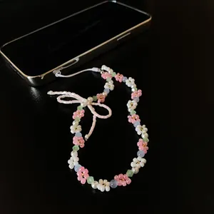 Detailed close-up of a sweet beaded necklace featuring pink crystal flowers and a pearl bow accent
