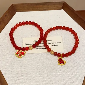 Red agate and rutilated quartz beaded bracelet with golden rocking horse charm