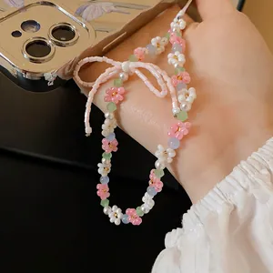 Macro detail of handmade floral bead necklace featuring delicate pink and white flower charms