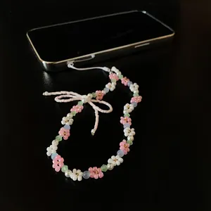 Detailed view of handmade beaded flower phone strap with pink bow accent