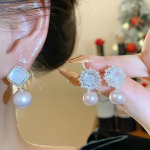 Close-up detail of elegant flower-shaped zircon and pearl earrings with shiny silver finish
