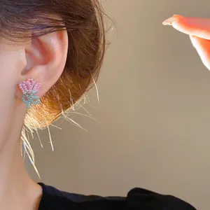Close-up view of handmade pink beaded tulip flower earrings worn on a model's ear in warm light.