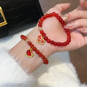 Close-up of elegant red agate and rutilated quartz bracelet with golden horse charm