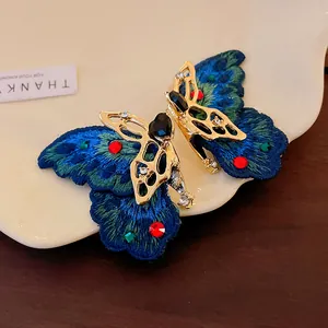 Dettaglio di orecchini a farfalla blu ricamati di lusso con una pietra a cuore