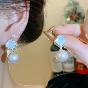 Elegant Korean-style pearl earrings with square CZ stud, shown worn and hand-held.