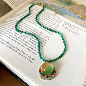 Close-up of a vintage French court style green beaded necklace with circular resin pendant