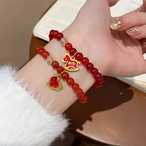 Detailed view of red agate beads and golden horse charm on a hand-worn bracelet