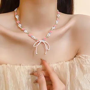 Macro detail of a sweet floral beaded necklace featuring a pink bow pendant on model