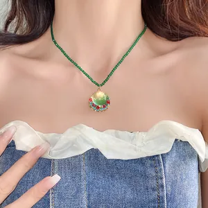Detail of vintage French green beaded necklace with circular resin pendant on model.