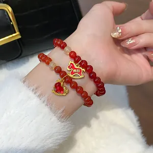 Detail of red agate beaded bracelet with golden horse charm on female wrist