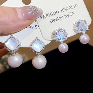 Macro detail of zircon flower and square opal earrings with round pearls