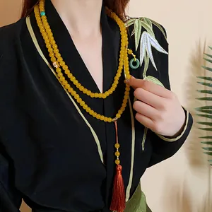 Detailansicht der gelben Perlenkette mit Quaste und grünem Ring im asiatischen Stil
