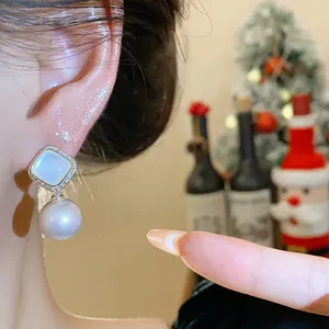 Detailed close-up showing an elegant pearl drop earring with zircon studs worn on ear