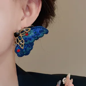 Primo piano di orecchino a farfalla ricamato blu con strass