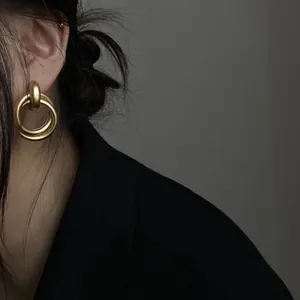 Elegante Nahaufnahme von vintage mattgoldenen Doppelkreis-Ohrringen an einem Modell