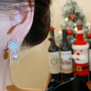 Close-up view of elegant silver needle zircon flower and pearl earrings worn on ear