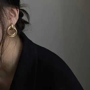 Nahaufnahme von goldenen Doppel-Ohrreifen im Vintage-Stil, getragen von einem Modell.