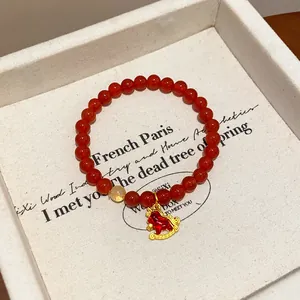 Detailed view of red agate bracelet with gold horse charm and rutile bead