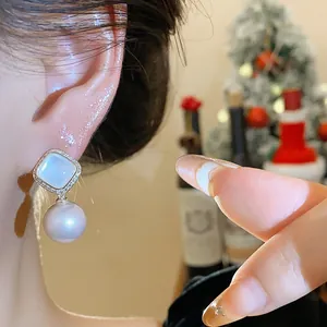 Detailed macro view of elegant pearl drop earrings with zircon embellishments on model ear