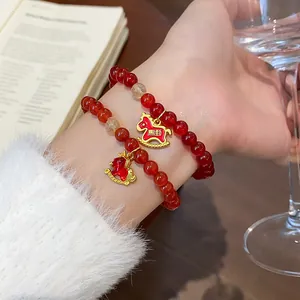 Close-up of red agate beaded bracelet featuring cute gold rocking horse charms