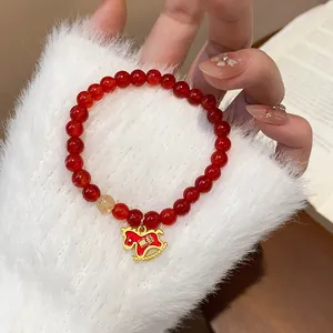 Close-up of red carnelian agate bracelet with golden horse charm and rutile quartz
