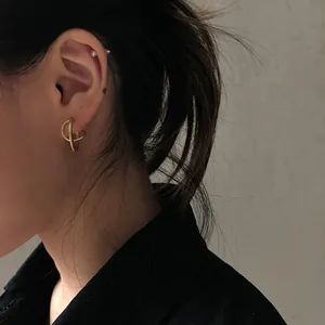 Detailaufnahme von goldenen geometrischen Doppelohrringen an einer Frau im Vintage-Stil