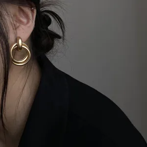 Detailansicht von Vintage-Doppelohrringen aus mattem Gold an einem Model in Schwarz.