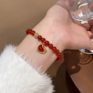 Detailed close-up of red agate beaded bracelet with a cute golden rocking horse charm