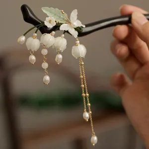 Gros plan d'une épingle à cheveux en bois avec muguet et glands en perles.