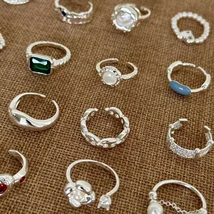 Vue détaillée de diverses bagues de mode argentées avec perles et cristaux sur jute.