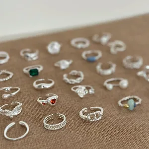 Collection de bagues ouvertes en argent avec accents de perles et pierres sur lin brun.