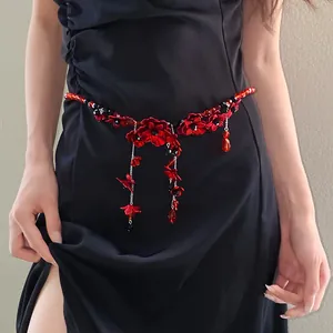 Macro detail shot of a red beaded flower tassel waist chain on a chic black dress