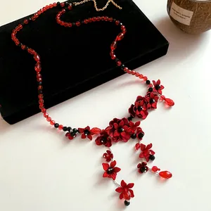 Close-up of red glass beaded floral tassel necklace on black velvet display box
