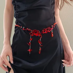 Detailed view of a red glass flower tassel waist chain on a black dress