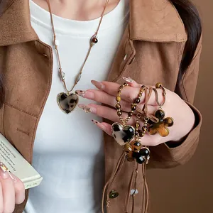 Close-up detail of Maillard style flower and heart necklaces with tiger eye beads.