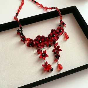 Close-up detail of red floral beaded waist chain with glass droplets in a display tray.