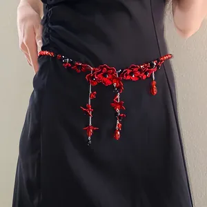 Detailed view of red glass beaded waist chain with elegant flower tassels on black dress