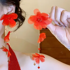 Close-up of elegant red chiffon flower tassel earrings worn by a model.