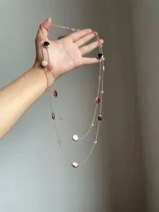 Detailansicht einer eleganten doppellagigen Goldkette mit runden Harz- und Glasperlen.