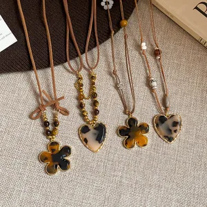 Close-up detail of flower and heart pendants on Maillard tiger eye stone necklaces